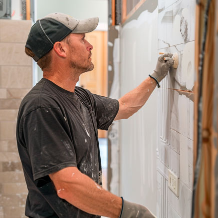 Ein Handwerker befestigt Fliesen an einer Wand in einem Innenraum